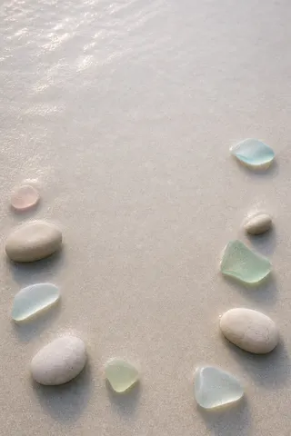 Pebbles and sea glass in an open circle on sand