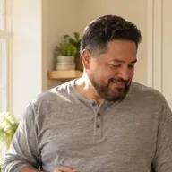 A man smiling down at his phone in a bright living room